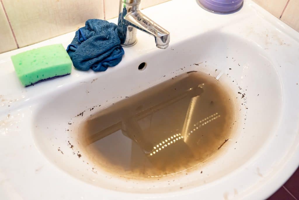 Clogged bathroom sink with dirty water